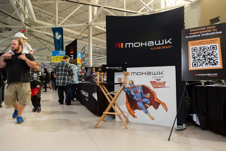 Mohawk College's information stall at Hamilton Comic Con 2022, with members of the crowd walking past it.