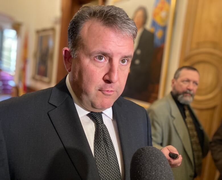 A man speaks to reporters inside the New Brunswick legislature.