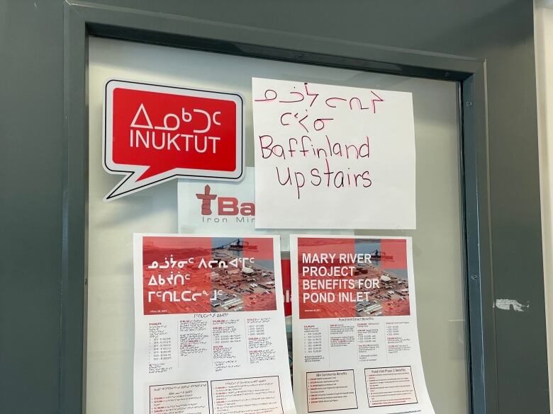 Red and white signs posted to a heavy steel door. 