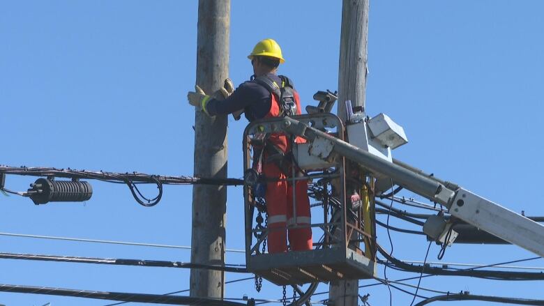 A linesman works from a truck crane bucket to repair a power line.