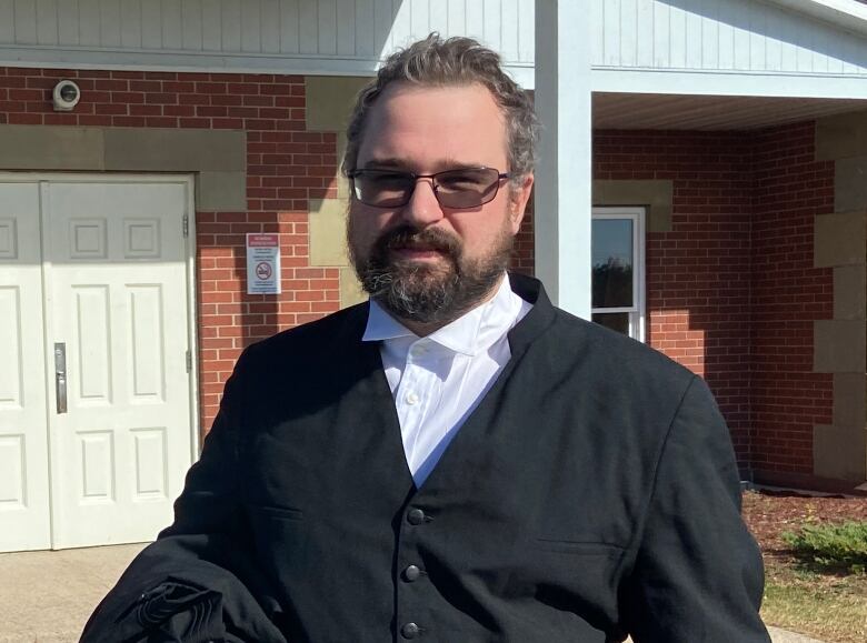 A man stands outside a brick building.