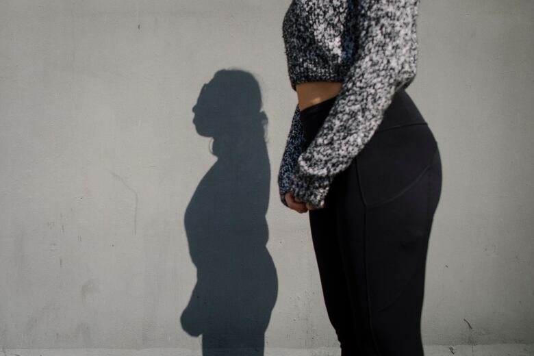 A picture of a woman's midriff and shadow.