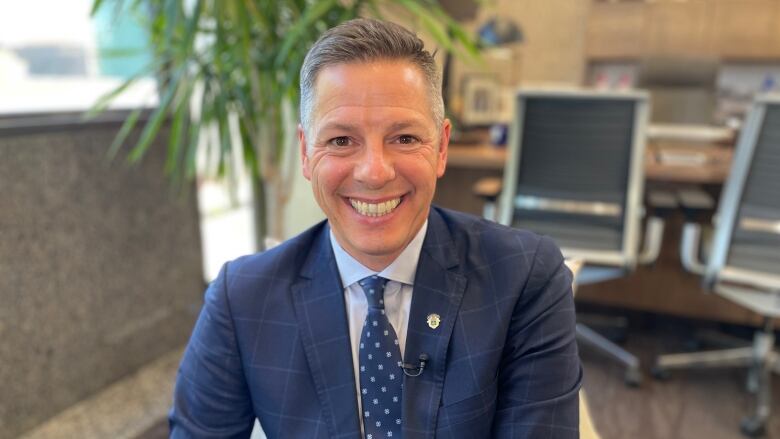 Man in blue suit with big smile looking at camera.