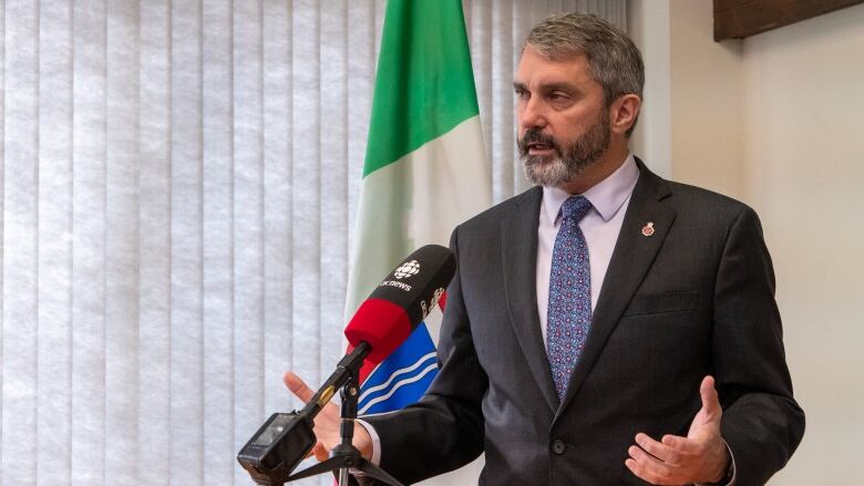 Silver-haired man in suit at podium.