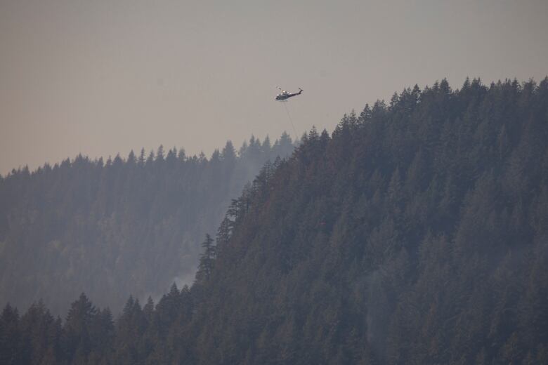 helicopter flies over Minnekhada Regional Park during a wildfire