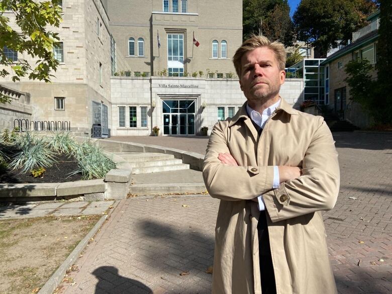 A man crosses his arms while standing in front of a school.