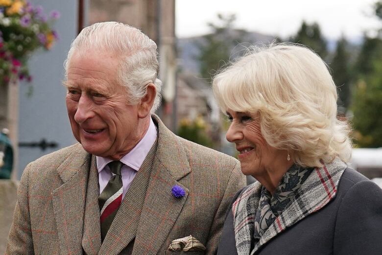 A grey haired man and blond woman standing side by side smiling