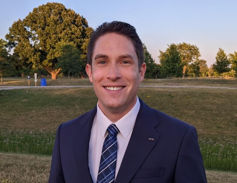 James Dorner in a suit in a park.