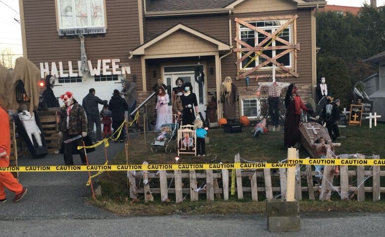 Picture of a house decorated with Halloween decorations, such as pumpkins, caution tape, scary figurines.