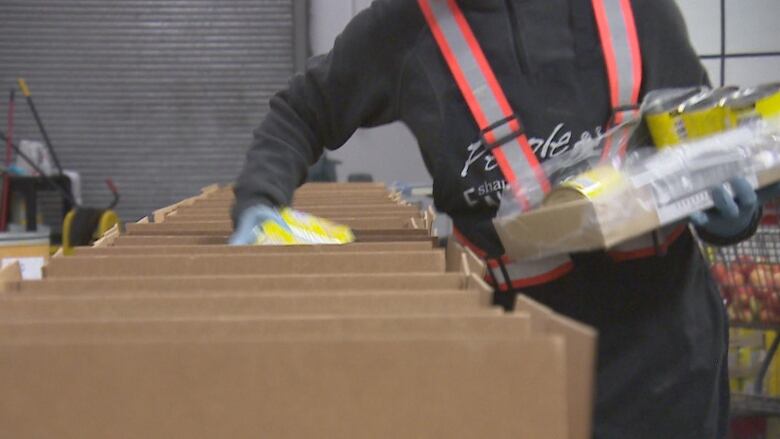 A volunteer places canned food in food hampers at the Regina Food Bank. 