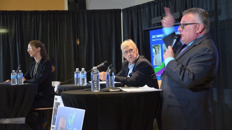 Richard Lafleur waves his arm in the air, while Joe Campbell looks on and Michelle Boileau looks straight ahead.