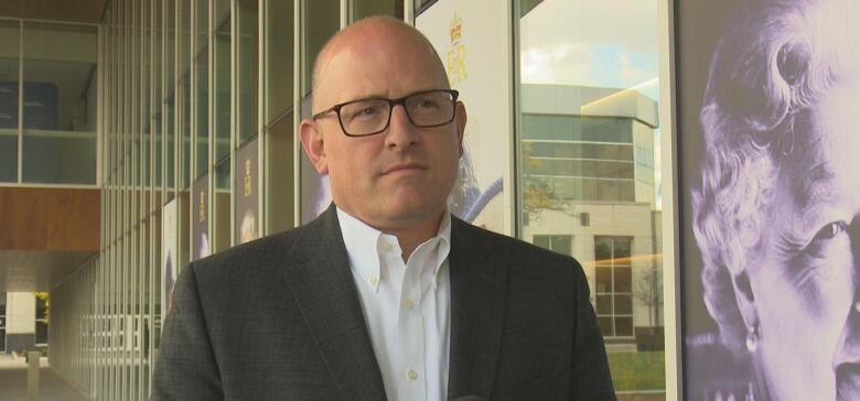 Drew Dilkens in a suit in front of glass building.