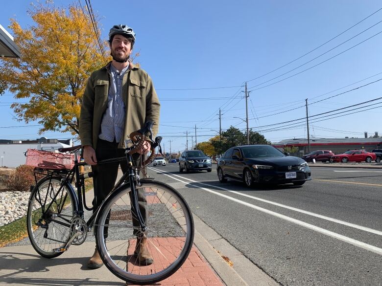 Man with bike beside painted bike lane.