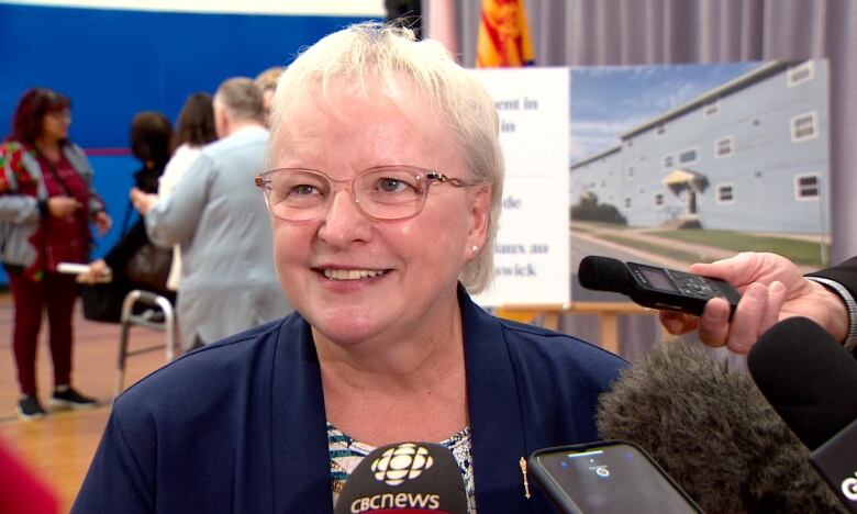 Smiling woman talks to a group of reporters. 