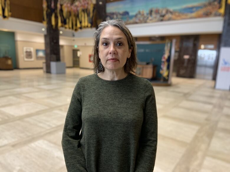 A waist-up shot of a person with long grey hair looking at the camera.