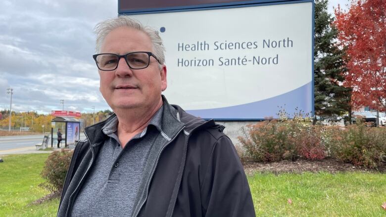 A man standing in front of a sign that says Health Sciences North.