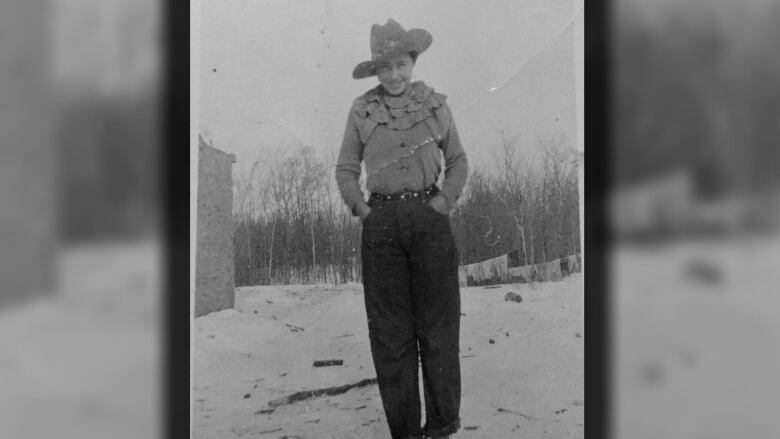 Old-looking photograph of woman in cowboy hat outside in winter, hand in pockets.