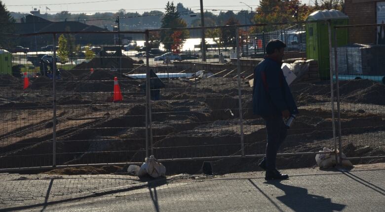 A man walks on Queen Street in Sault Ste. Marie past the site of the new downtown plaza, currently under construction. 