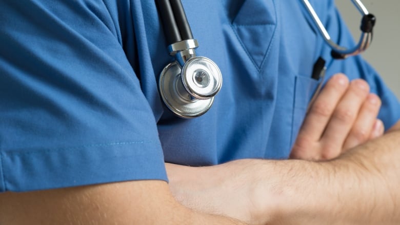 A health care worker in scrubs with a stethoscope around their neck.