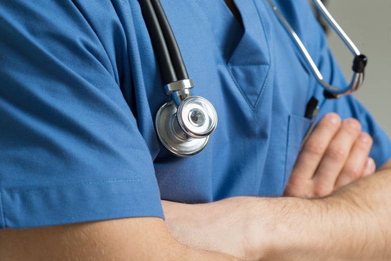 A health care worker in scrubs with a stethoscope around their neck.