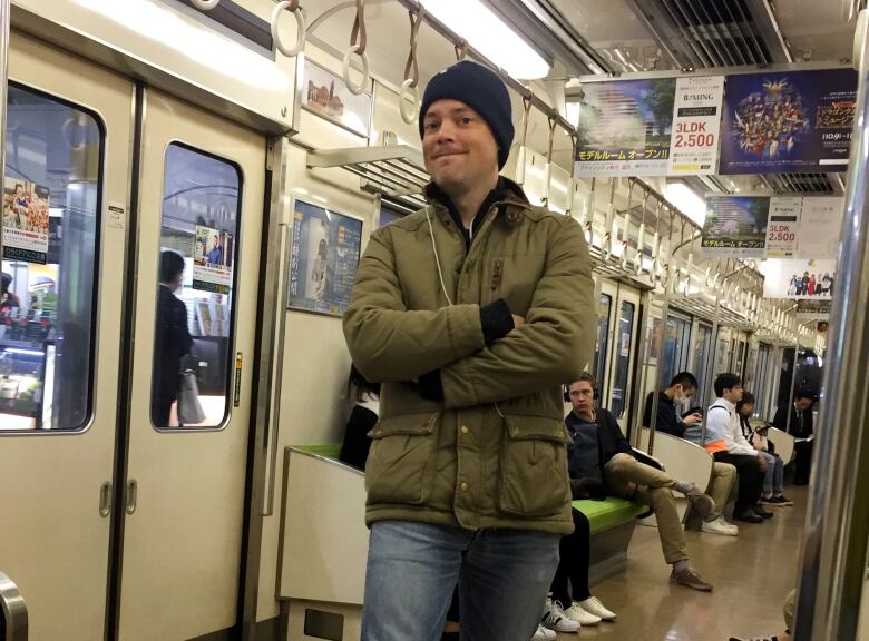 Man wearing winter hat and jacket abord a clean train with Japanese signage