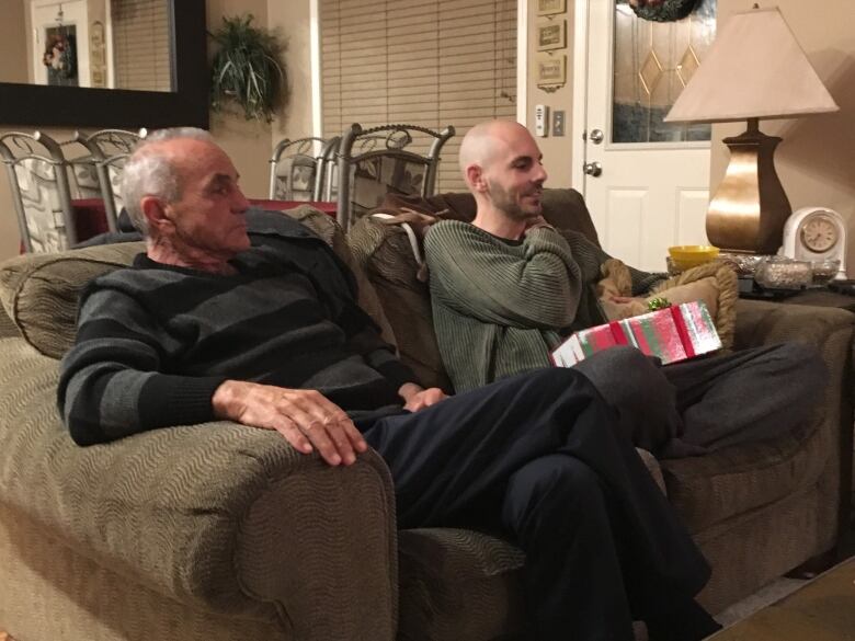 Two men sit on a couch together.