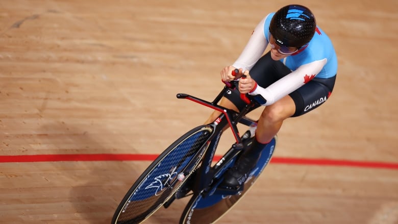 A woman in a cycling uniform rides on a track.