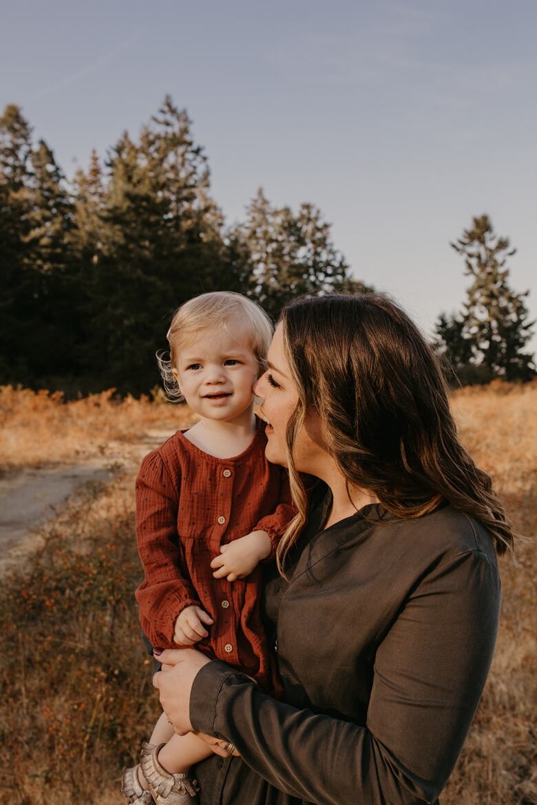 A woman holds a young child outdoors