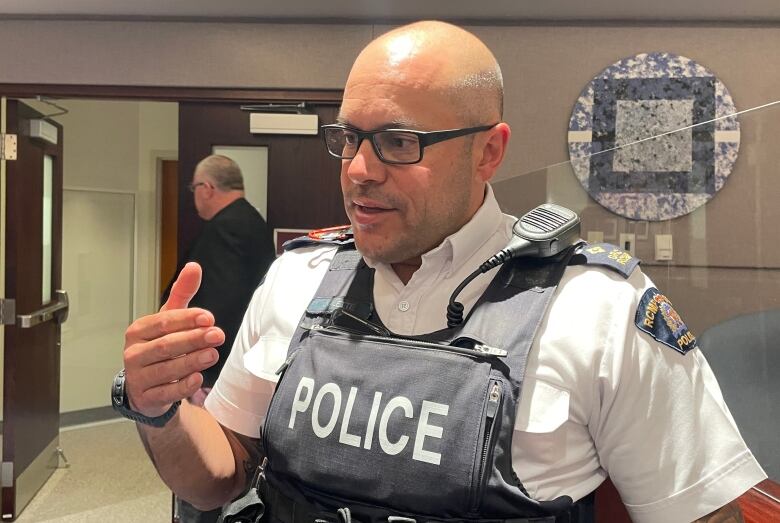 A uniformed police officers speaks to someone while standing inside a building.