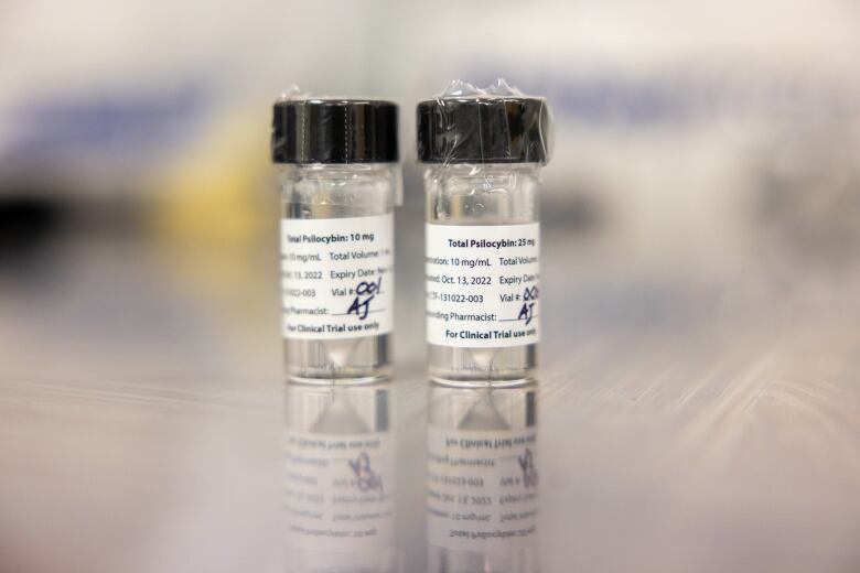 Two small vials are seen on a smooth surface.