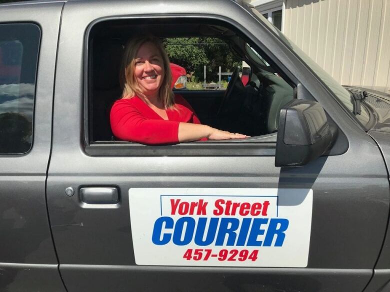 A close-up of a silver truck with a sign on the driver's side door that says 