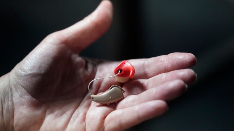 A hearing aid is held in a woman's hand. 