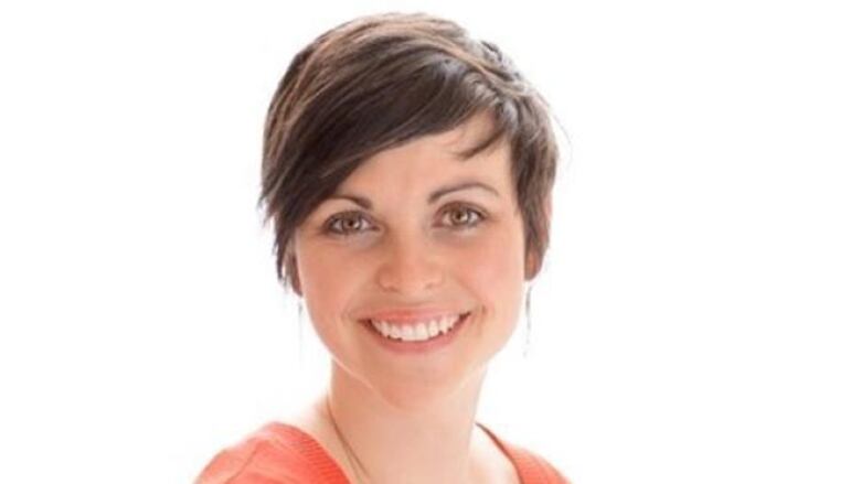 A close up photo of a smiling woman in front of a plain background. 