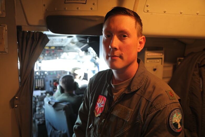 A man in a military uniform stands in front of the cockpit of an AWACS aircraft. 