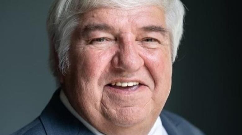 a very close up shot of a person smiling. they have short white hair.