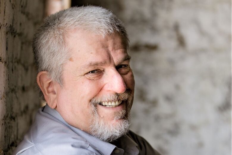 A man smiling with his arms crossed.