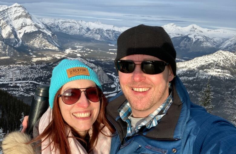 A woman and a man taking a selfie with the Canadian Rockies behind them.