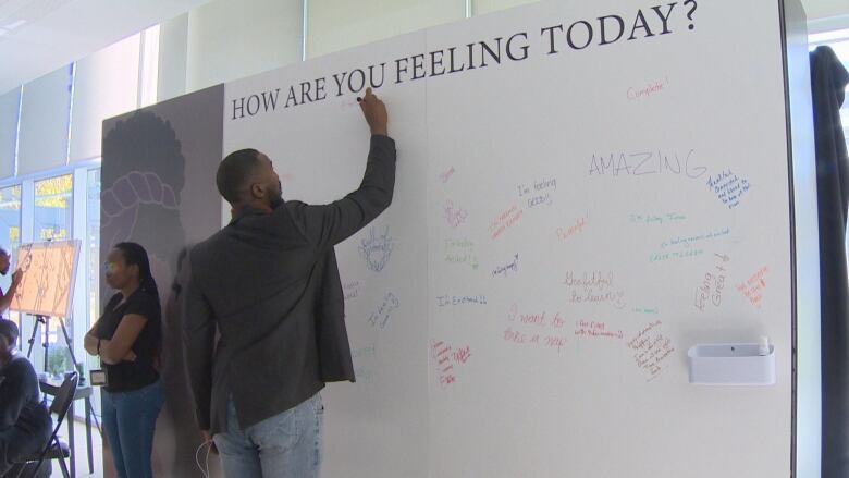 A man writes an answer on a white board below the question: 