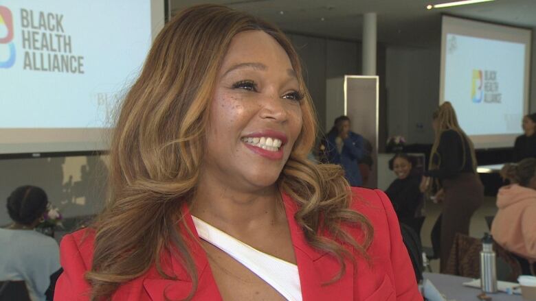 Tracey Moore shown smiling and wearing a red blazer. 