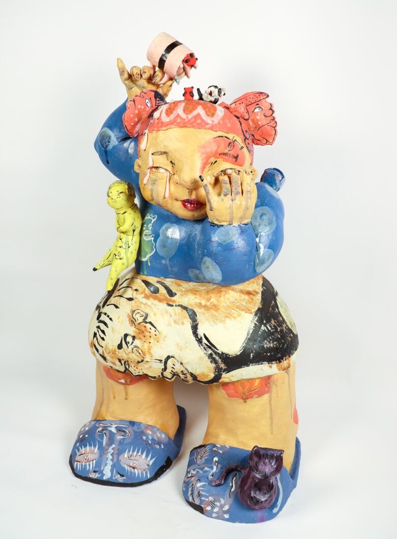 Photo of a ceramic form of a pudgy child with tangerine pigtails.