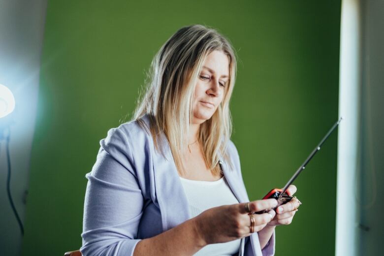 A woman holds an electronic device.