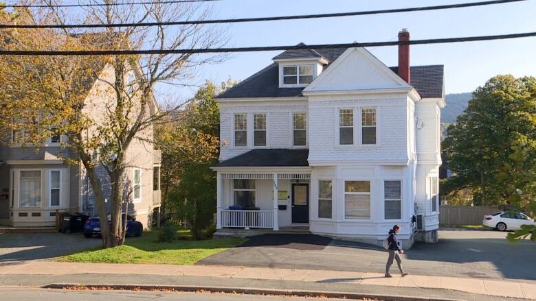 A white two-storey home in St, John's. The tiles on the roof are grey, and there are nine windows across the front of the home.