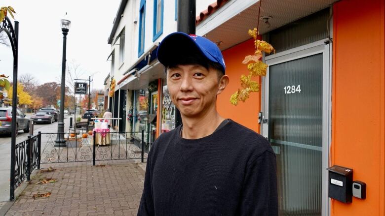 man stands in front of orange building 