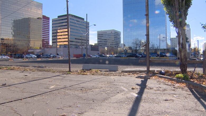 A view of an empty parking lot, with buildings behind it.