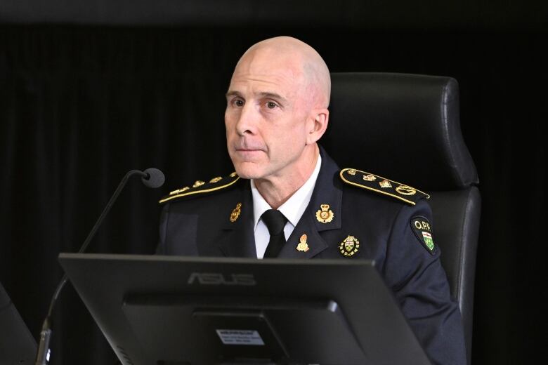 A police officer in uniform speaks at a microphone.