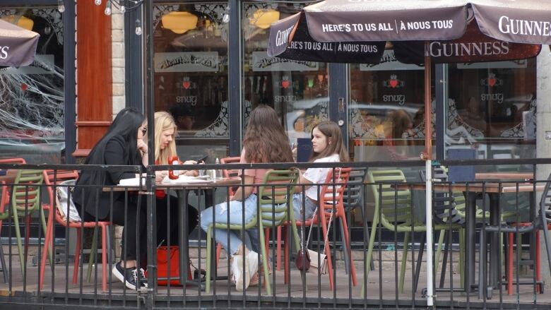 Four people, three of them without coats, on a pub patio.