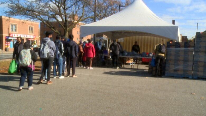 People lining up outside a tent to receive food