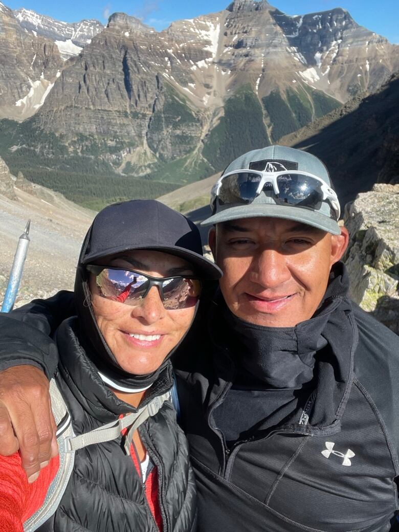 A woman standing in front of a mountain with her brother beside her. 