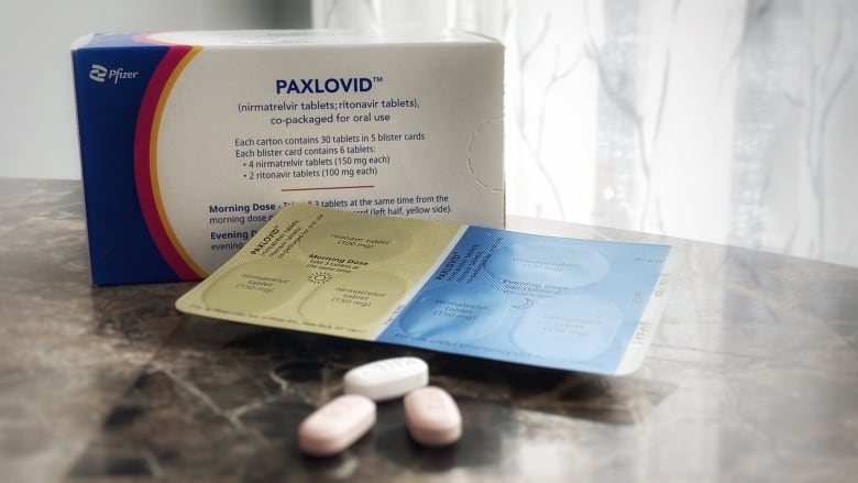 A box saying 'Paxlovid' with a strip of tablets in front of it.