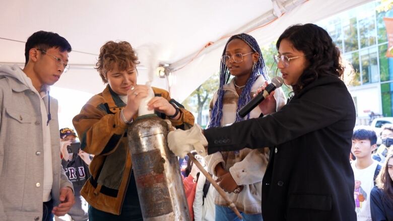 UBC student society president Eshana Bhangu, right, helps students, chosen at random, remove items from a time capsule opened on Oct. 28, 2022, 50 years after being buried to mark the 'great trek' student protest at UBC in 1922.